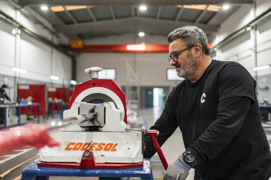Opérateur debout à une machine de découpe, en atelier