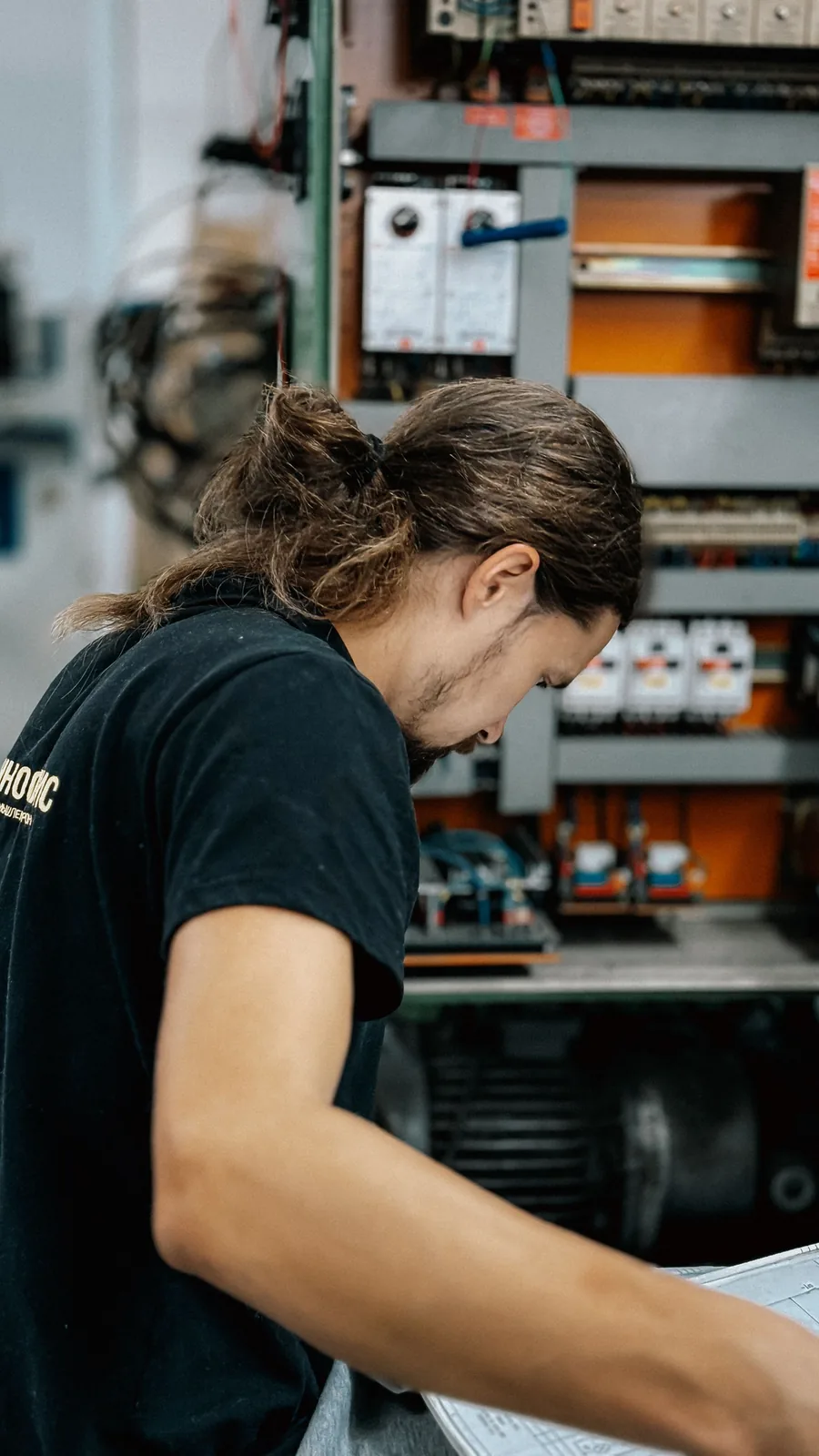 Technicien penché sur un plan, devant une armoire électrique
